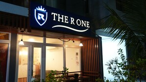 A hotel named "THE ONE" with a prominent sign, a reception area visible through the glass doors, and a view of the outdoors. - The R One (Hulhumalé)