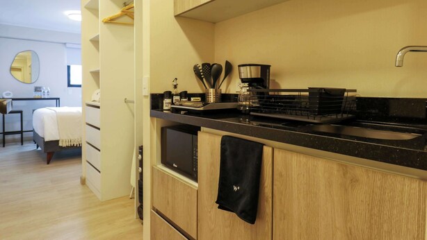 A compact kitchen with wooden cabinets, a black countertop, and a coffee maker. - w Fascinating Loft in the Heart of Miraflores (Lima)