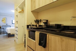 Uma cozinha compacta com armários de madeira, bancada preta e cafeteira.