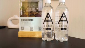 A brochure titled 'DESCUBRE PERU' with a QR code, two water bottles labeled 'andea', and a white vase on a table. - w Fascinating Loft in the Heart of Miraflores (Lima)