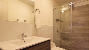 A modern bathroom with a glass shower enclosure, a white sink, and a wooden vanity. - w Fascinating Loft in the Heart of Miraflores (Lima)