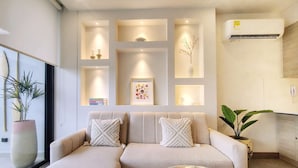 Een moderne woonkamer met een modulaire bank, een glazen salontafel en ingebouwde planken met decoratieve objecten.