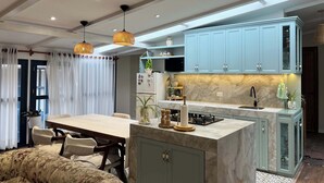 Una cocina moderna con armarios azul claro, encimera de mármol y una isla central con estufa a gas.