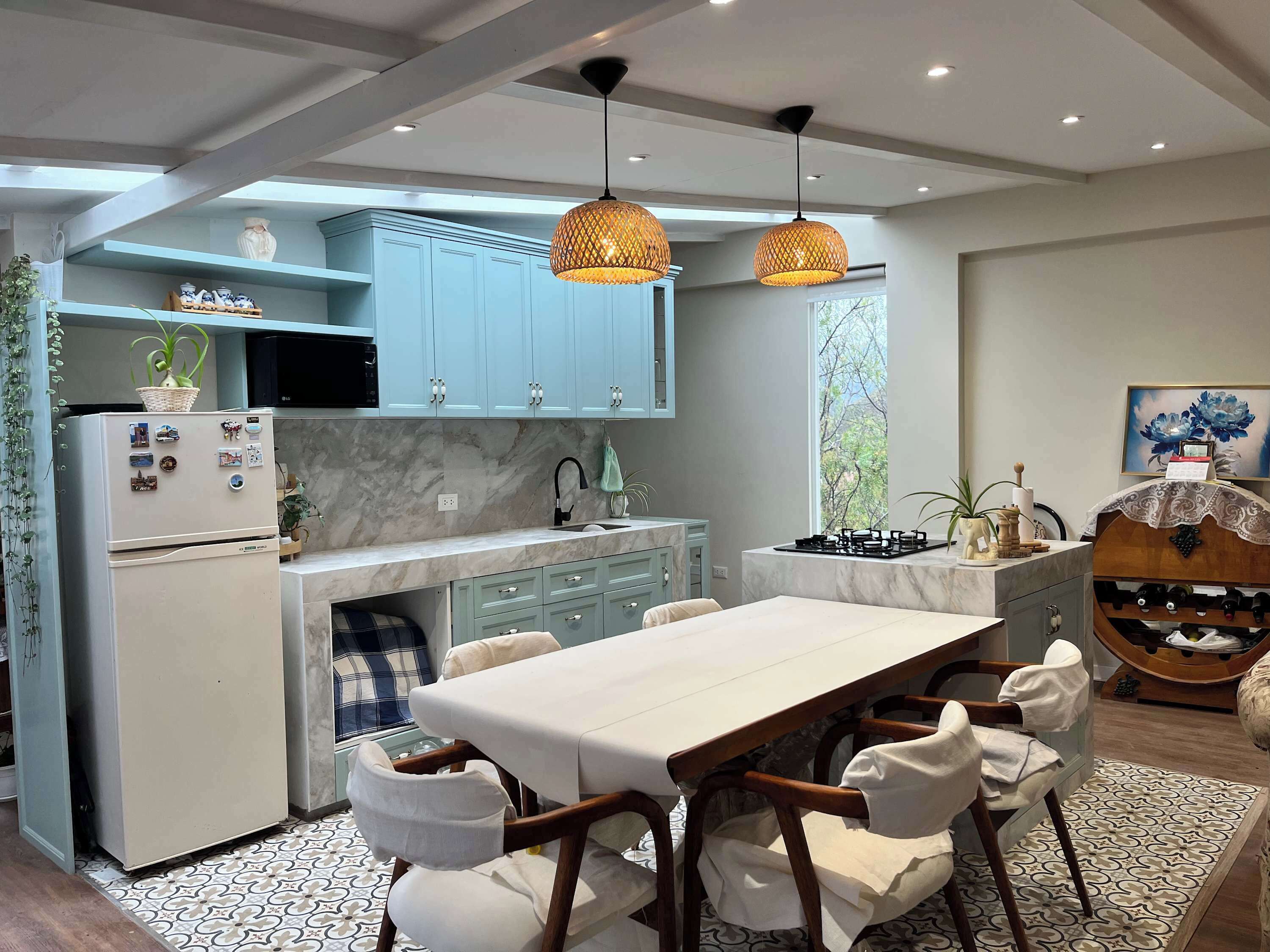 Una cocina moderna con armarios azul claro, una isla central e iluminación colgante.