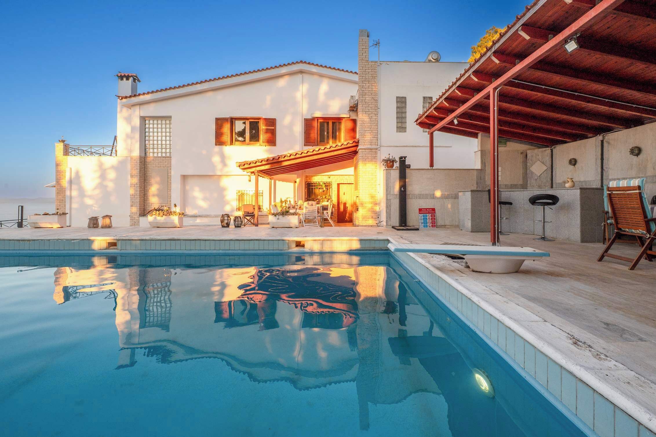 Une maison à deux étages dotée d’une piscine, d’un espace extérieur aménagé et d’un patio couvert.