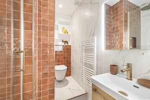 A modern bathroom with a white sink, a gold faucet, and a white toilet. - Garbottino, studio entirely renovated (París)