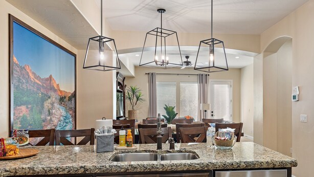 A kitchen with granite countertops, a stainless steel sink, and a dishwasher. There is a dining area with wooden chairs and a table. - Pebble Beach Retreat At Coral Ridge Resort 4 Bedroom Townhouse (Washington)