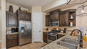 A kitchen with dark wooden cabinets, stainless steel appliances, granite countertops, and a double sink. - Pebble Beach Retreat At Coral Ridge Resort 4 Bedroom Townhouse (Washington)