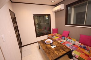 Une pièce de taille modeste, avec une table en bois, un canapé matelassé aux couleurs vives et une fenêtre équipée de stores.