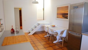 Une cuisine moderne dotée d’un réfrigérateur en acier inoxydable, de meubles blancs et d’un coin repas avec des chaises blanches.