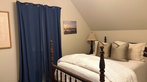 A bedroom with a wooden bed frame, a white bedspread, and a blue curtain. - Penny Lane-WALKING DISTANCE TO SQUARE & GROVE (Oxford)