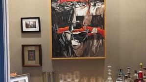 A room with a large abstract painting on the wall, a wooden table with glasses and bottles, and framed photos on the wall. - Penny Lane-WALKING DISTANCE TO SQUARE & GROVE (Oxford)