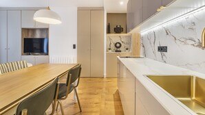 Eine moderne Küche mit Holztisch, Stühlen, einem Einbauofen und einer Marmor-Spritzschutzwand.