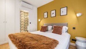 Ein Schlafzimmer mit einem Bett, einer flauschigen, braunen Decke, einem Kopfteil und einer Wand mit drei gerahmten Bildern.