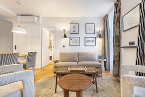 A modern living room with a sofa, two armchairs, a coffee table, and a TV stand with a small table and lamp. - Fantasia, 1BR/1BA, 4 people (París)