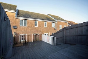 A residential building with a brick facade, a wooden deck, and a white fence. - Vacant Nest  | Cleveland Close | Central | Parking (County Durham)