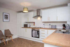 A modern kitchen with white cabinets, a microwave, a toaster, and a sink.