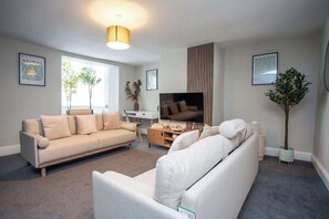 A modern living room with a sofa, TV, and decorative plants.