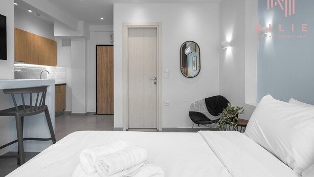 Una habitación de hotel moderna con una cama, un escritorio, una silla y un baño.