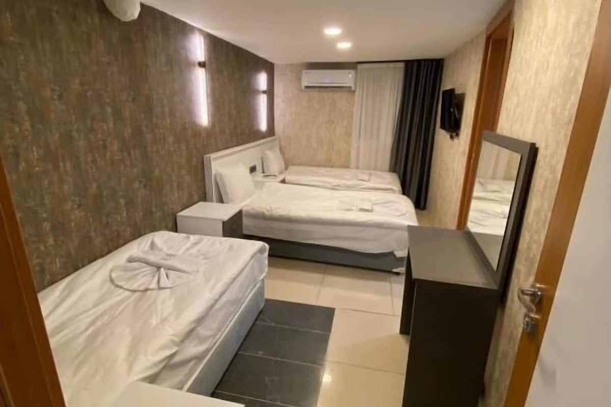 A hotel room with two beds, a small desk, a mirror, and a door.