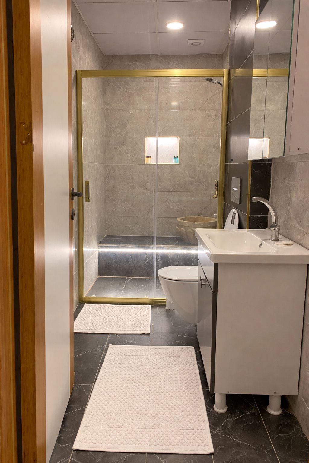 Un baño moderno con ducha envuelta en vidrio, lavamanos blanco y retrete.