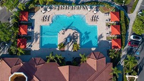 Eine Vogelperspektive eines Resorts mit einem zentralen Schwimmbad, mehreren Liegebereichen und einem Parkplatz.