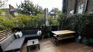A wooden deck with a sofa, a small table, and a bench. - Victorian Townhouse in Barnsbury - centrally located, modern and pet-friendly! (London)