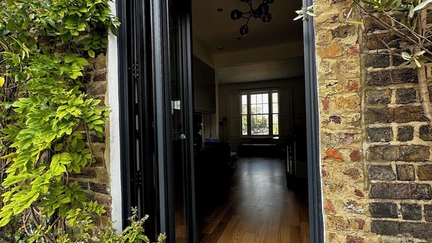 A modern interior with a wooden floor, a black-framed sliding door, and a visible kitchen area. - Victorian Townhouse in Barnsbury - centrally located, modern and pet-friendly! (London)