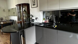A modern kitchen with grey cabinets, a black countertop, and a wooden dining table. - Victorian Townhouse in Barnsbury - centrally located, modern and pet-friendly! (London)