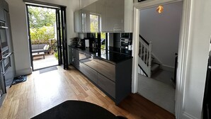 A modern kitchen with black cabinets, a wooden countertop, and a view to a patio area. - Victorian Townhouse in Barnsbury - centrally located, modern and pet-friendly! (London)