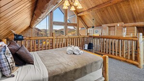Una camera accogliente con un letto grande, soffitto in legno e vista sulle montagne.