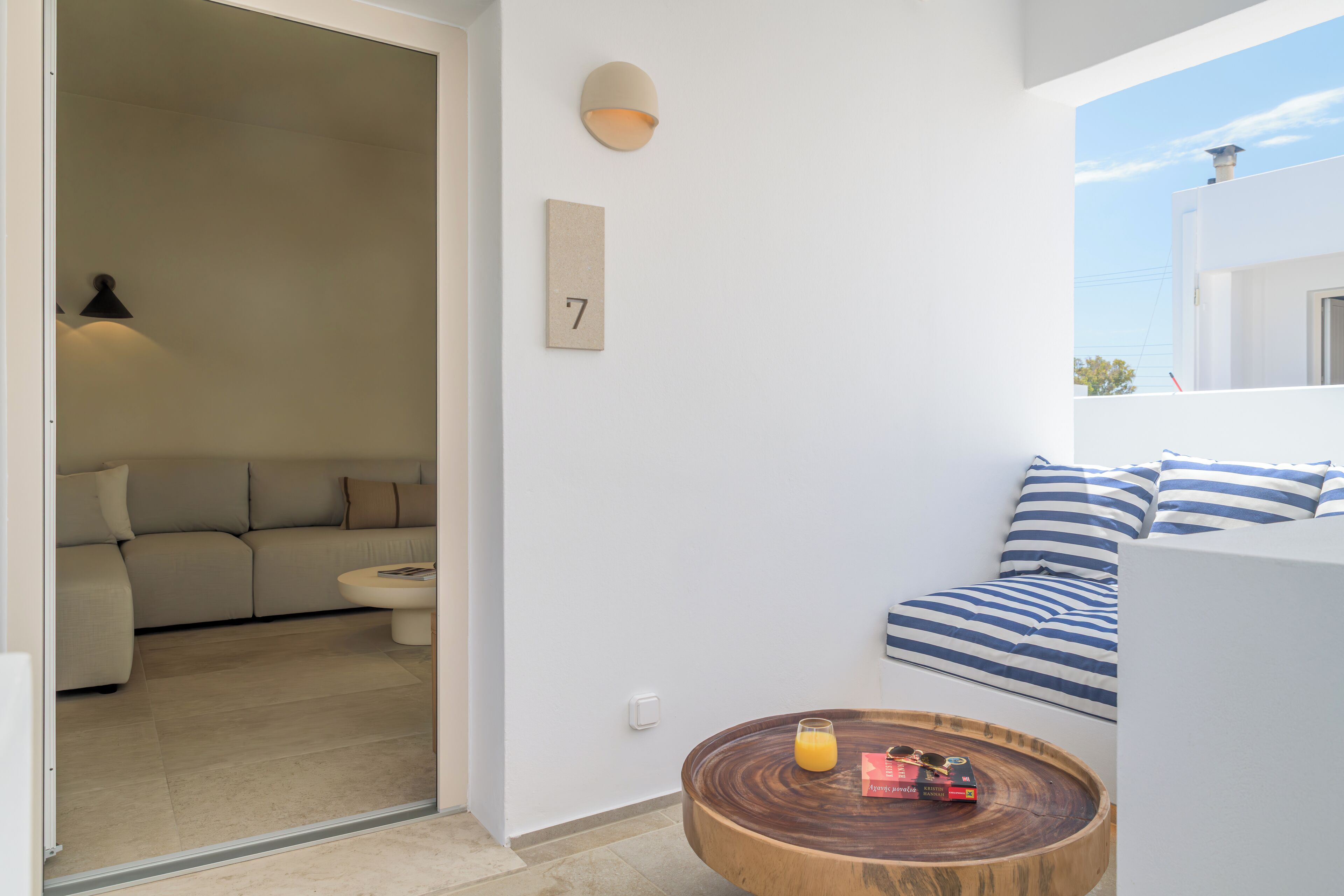 A modern living room with a sofa, a round wooden coffee table, and a wall-mounted lamp.