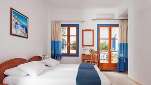 A hotel room with a large bed, a desk, a chair, and a balcony with curtains. - HOTEL ELENI (Milos)