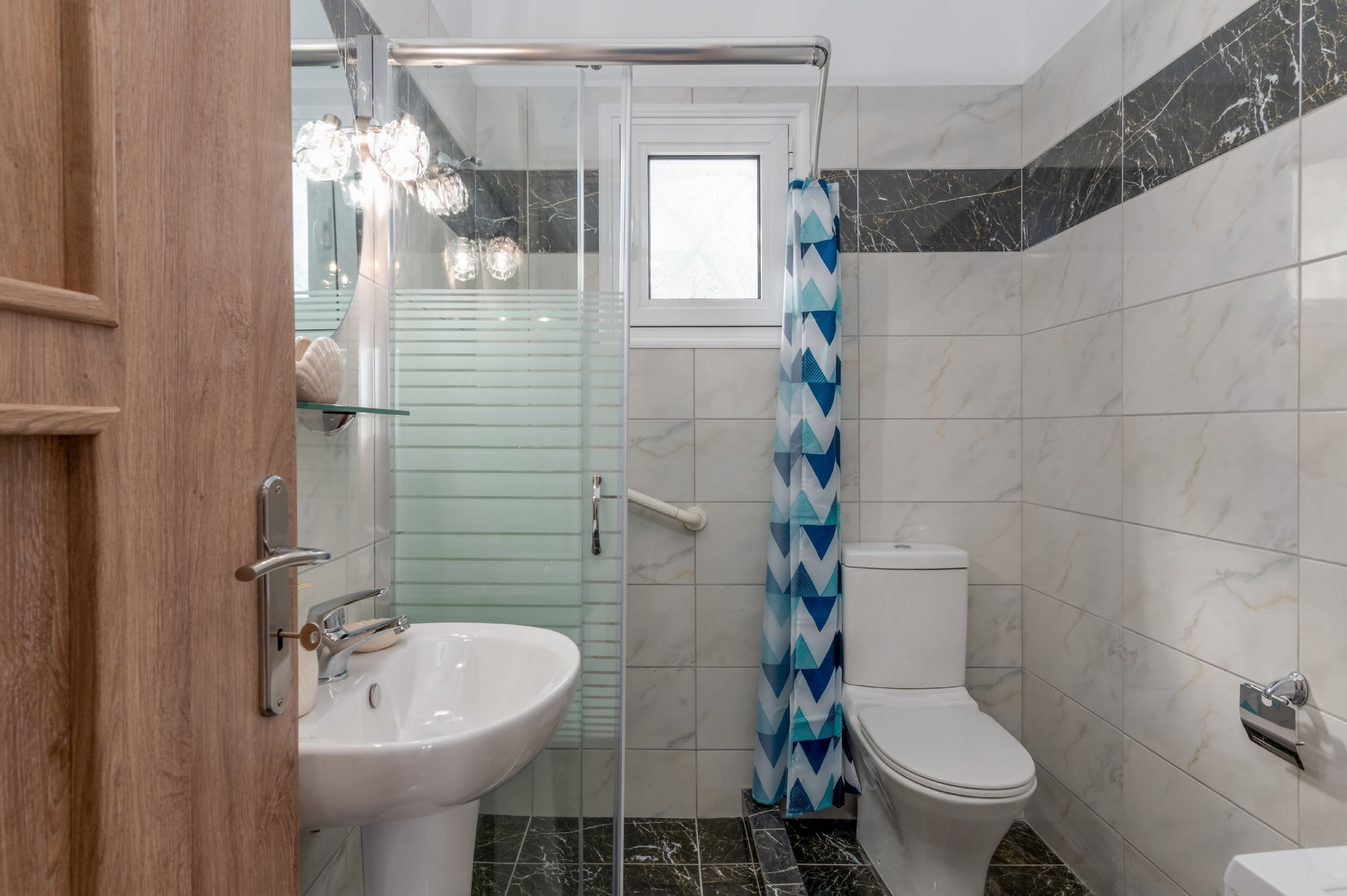 A bathroom with a glass shower enclosure, a white toilet, and a sink.