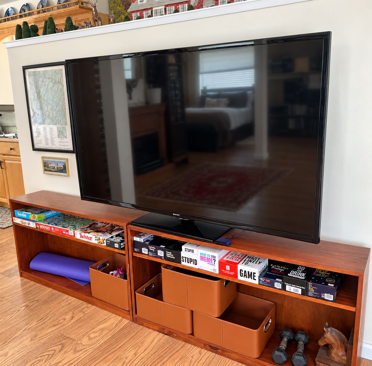 Ein Flachbildfernseher auf einem Holzboden mit Stauraumschubladen darunter.