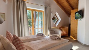 Een slaapkamer met twee bedden, een houten plafond, een televisie en een raam met gordijnen.