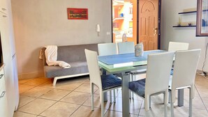 Ein Essbereich mit Tisch und Stühlen, einer Couch und einer Tür zu einem Außenbereich.