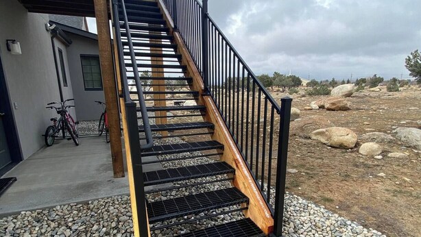A staircase with wooden steps and black railings leading to a building.