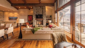 Un salón acogedor con chimenea, asientos cómodos y un amplio ventanal con vistas a la ciudad.