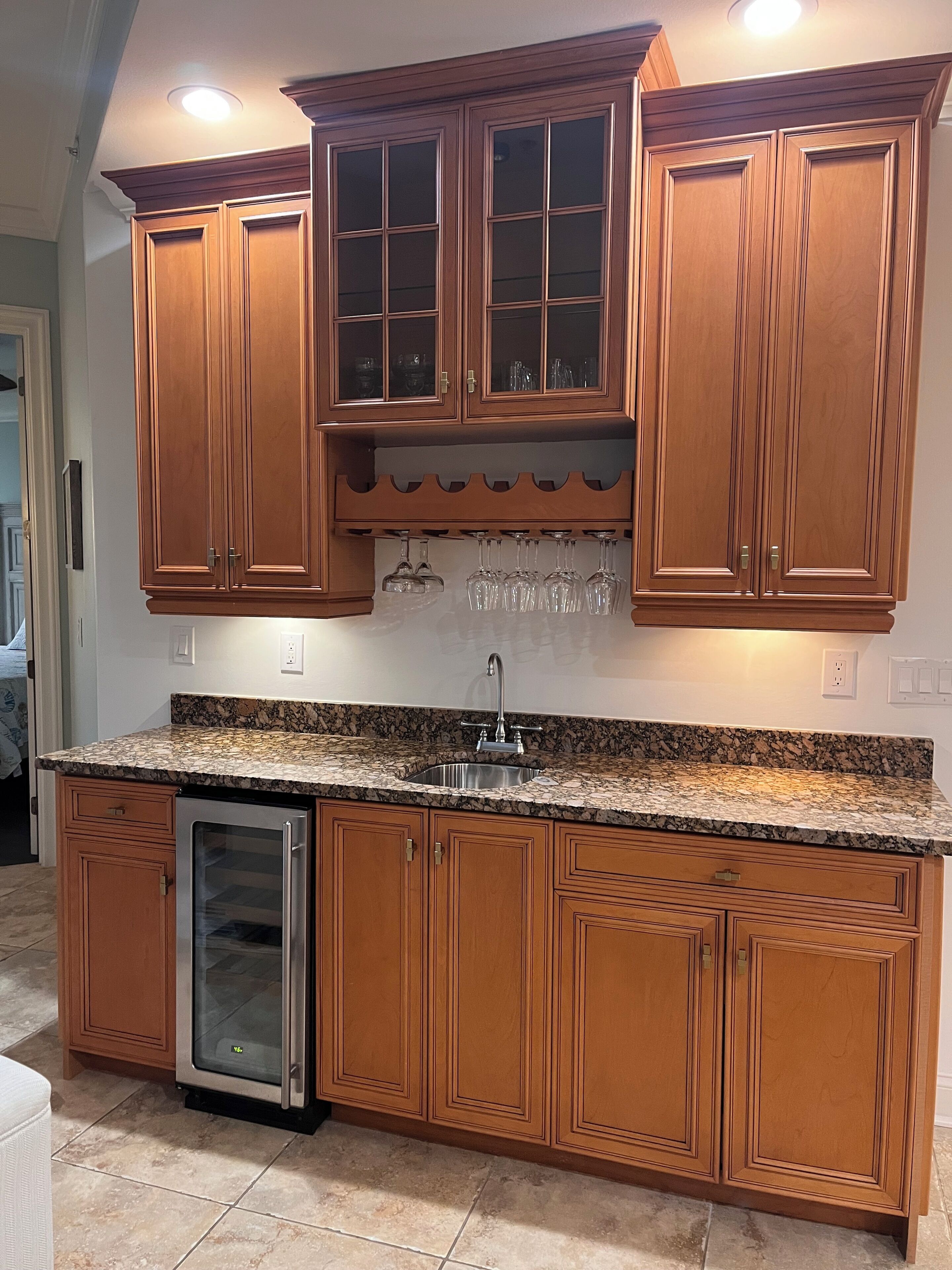 A kitchen with wooden cabinets, a granite countertop, a stainless steel sink, and a built-in dishwasher.