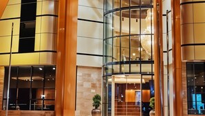 Ein moderner Hotel Eingang mit einer geschwungenen Glasfassade, einem auffälligen Schild mit der Aufschrift „Prime Hotels“ und einem gut beleuchteten Innenraum, der durch das Glas sichtbar ist.