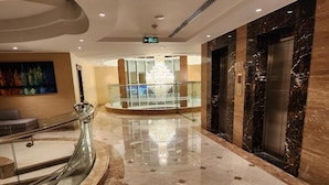 Eine moderne Lobby mit Marmorboden, Glastrennwand und einer Kristallleuchtre.