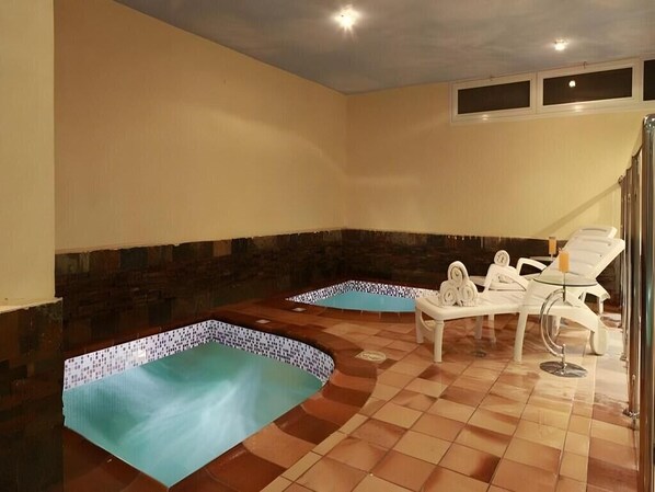 Un espace bien-être comprenant deux bains à remous et des chaises longues.