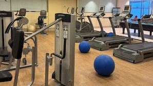 Ein Fitnessstudio mit Laufbändern, Krafttrainingsgeräten und Übungsbällen.