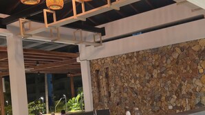 Un restaurante con pared de piedra, una mesa de madera y sillas de mimbre.