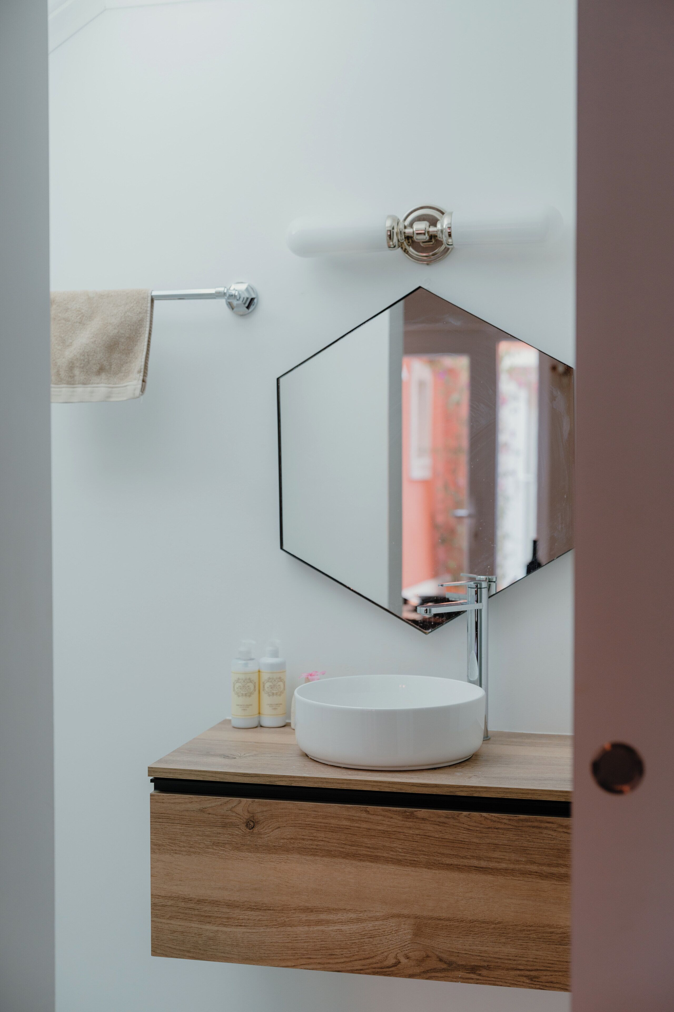 A bathroom with a round sink, a mirror, and a towel rack.