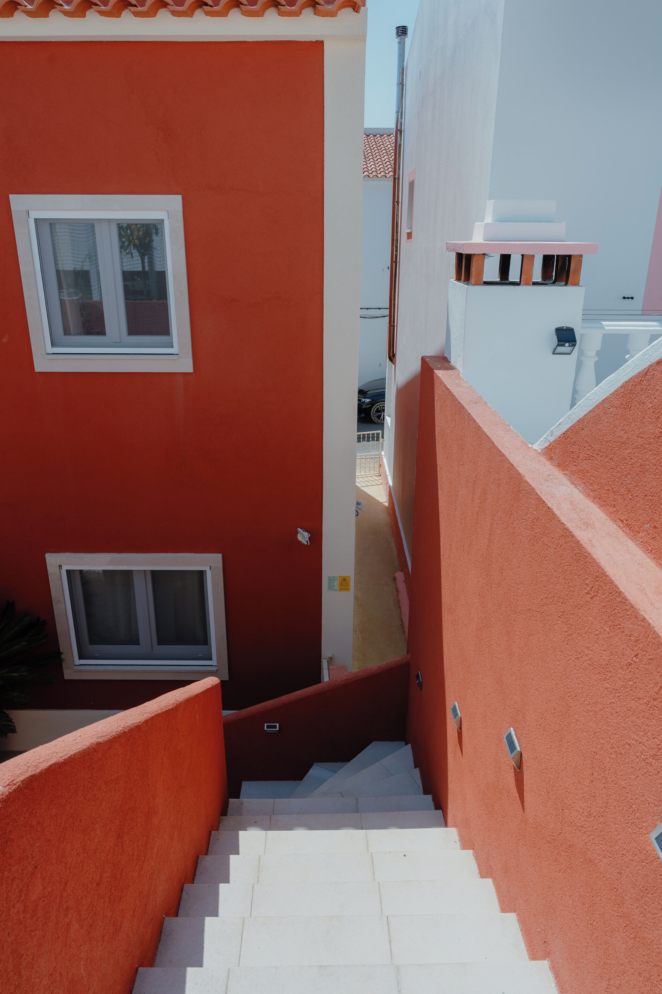A staircase leading to a residential building with a red exterior and white windows.
