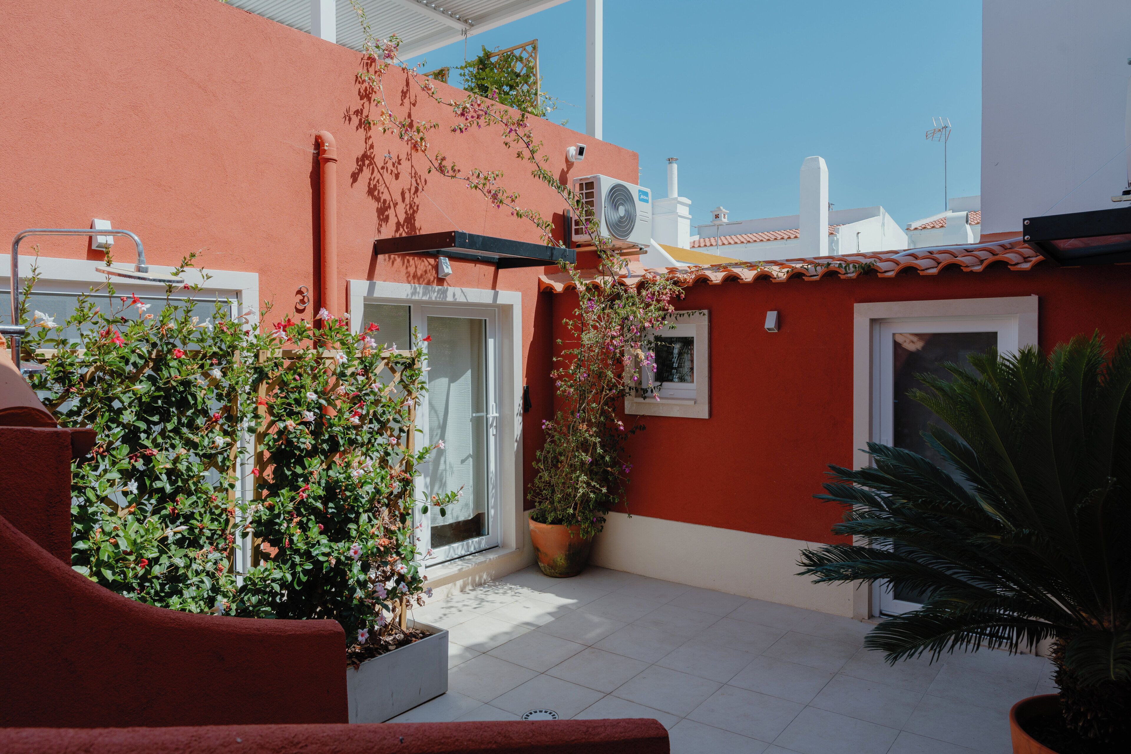 A red building with a white door, a window, and a potted plant.