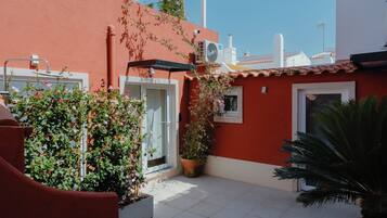 A red building with a white door, a window, and a potted plant.