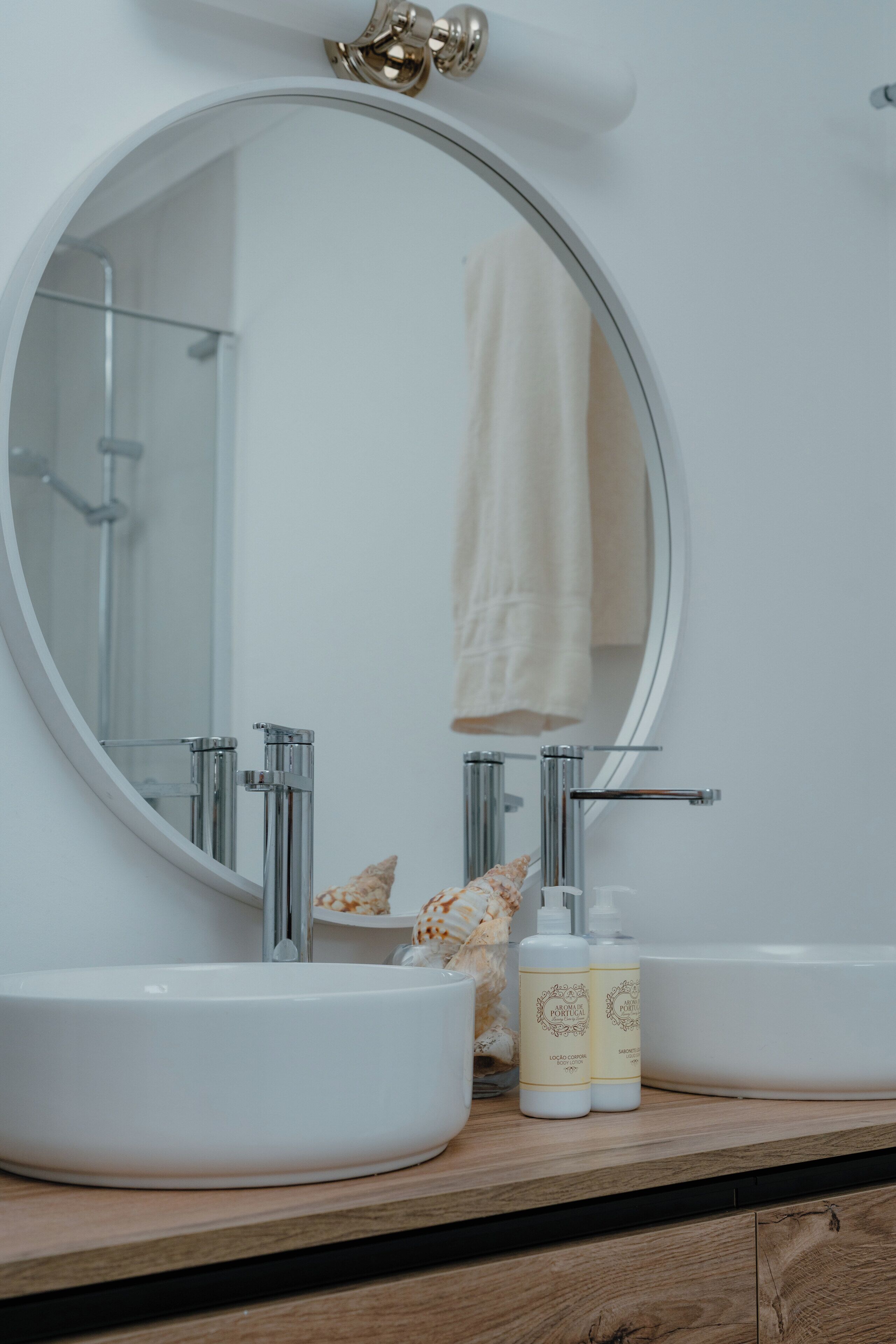 A bathroom with a round mirror, two sinks, and a towel rack.
